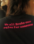 Black shirt with red text 'We all broke our rules for someone' on a blurred background