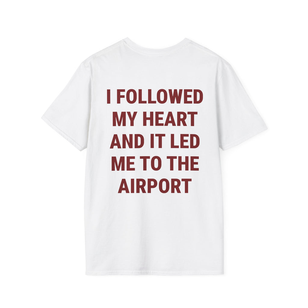 A white short-sleeve t-shirt with bold dark red text on the back that reads 'I FOLLOWED MY HEART AND IT LED ME TO THE AIRPORT', shown against a plain white background.