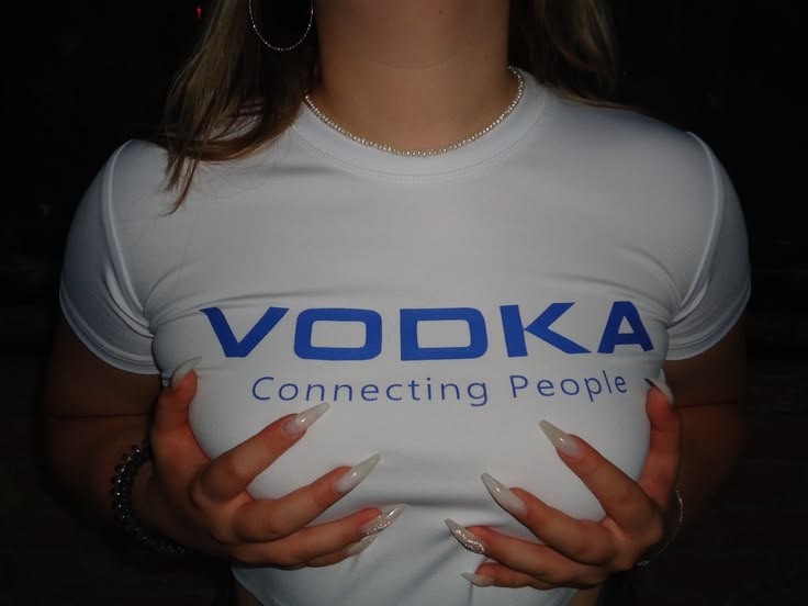 A person wearing a white short-sleeve t-shirt with 'VODKA Connecting People' printed in blue across the chest, photographed in a dark setting.